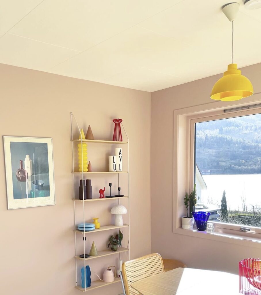 Morning light into a pink dining room with Scandinavian furniture and colorful details.
