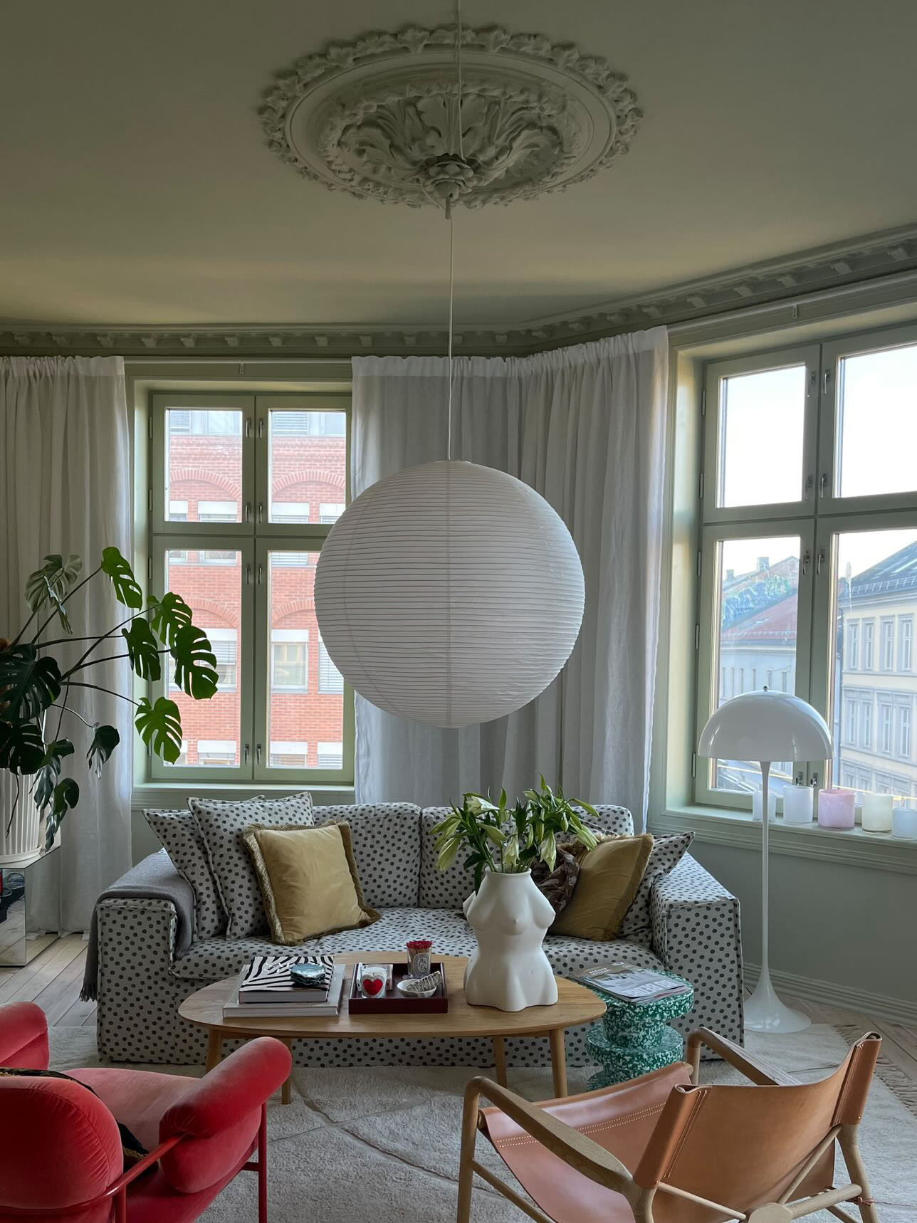 Green Scandinavian living room with colors, dotted sofa and big rice lamp.