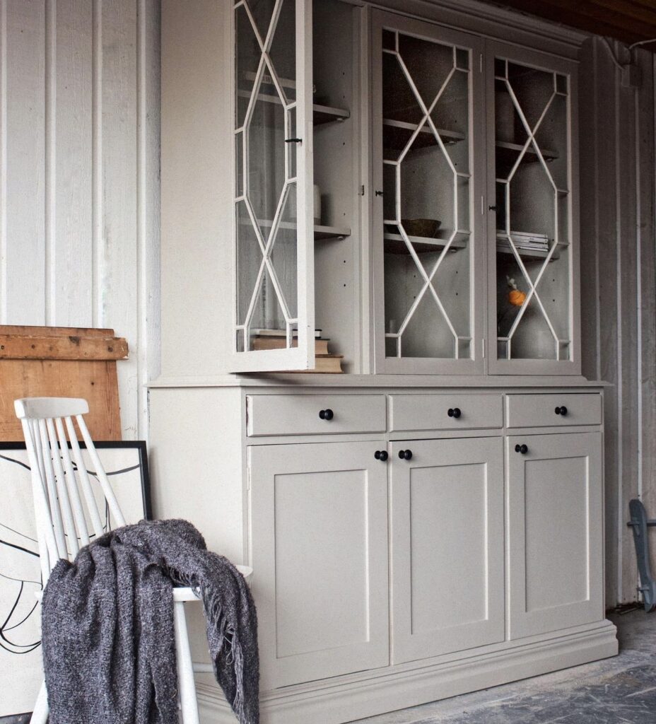Big renovated greige cabinet with glass door in Scandinavian home.