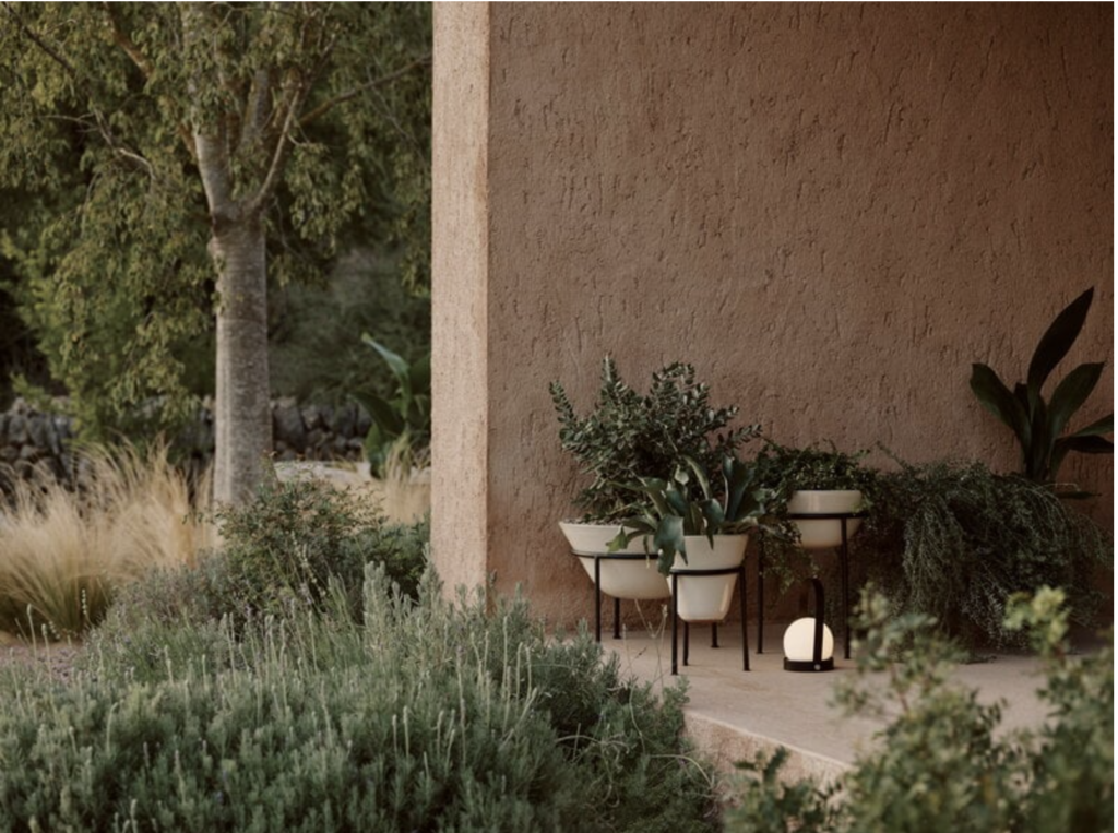 Outdoor space with earthy colors and lots of plants and a portable lamp