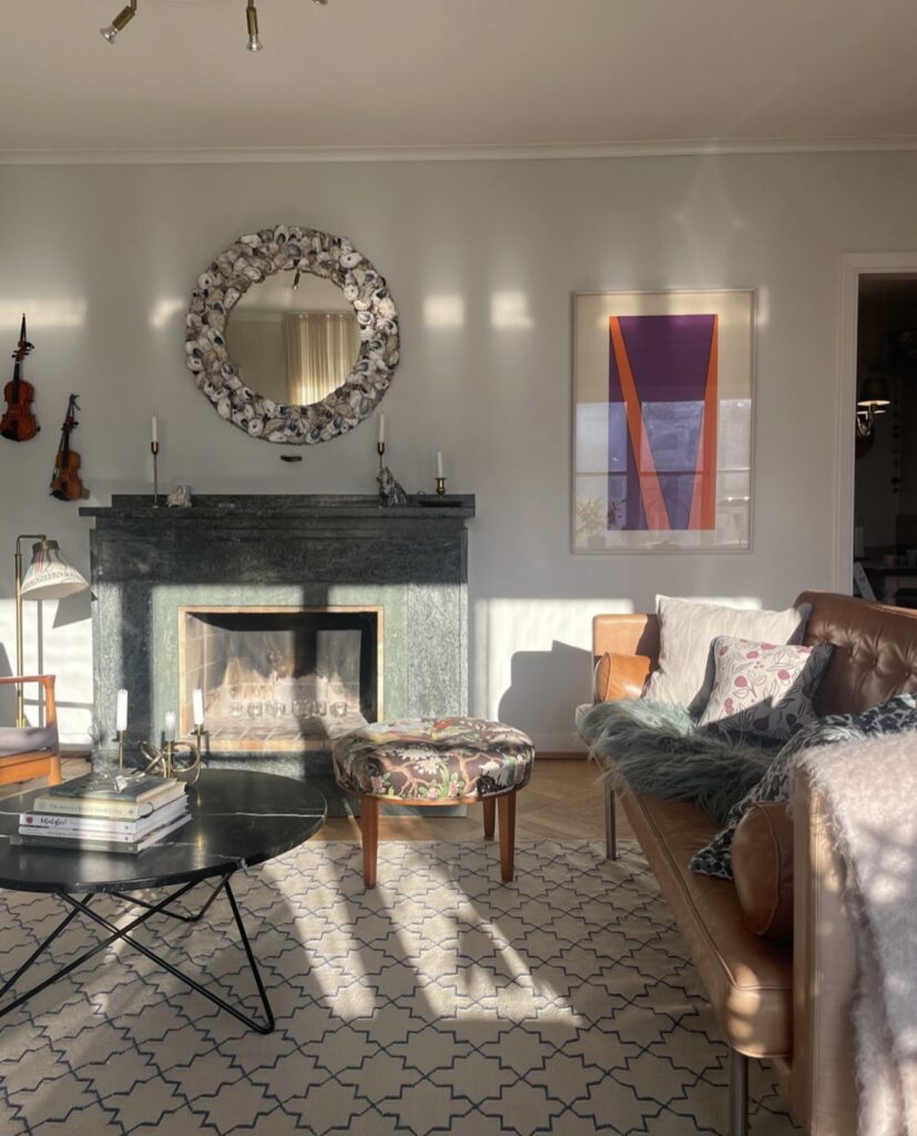 Scandinavian living room with a large marble fireplace and sun streaming in thorugh the windows.