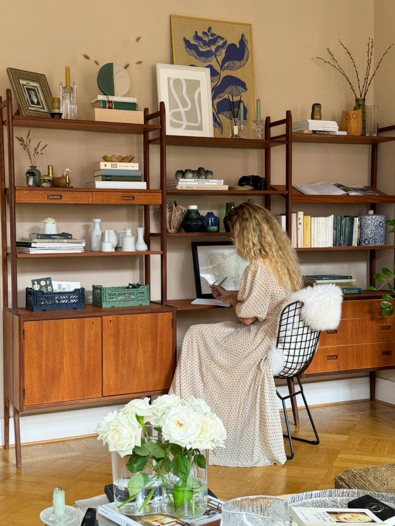 Vintage shelving system in teak wood styled ina Scandinavian apartment with beige walls and design details