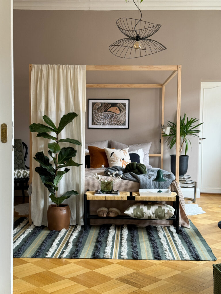 Four poster bed frame in wood in a Scandianvian beige, green, brown themed apartment