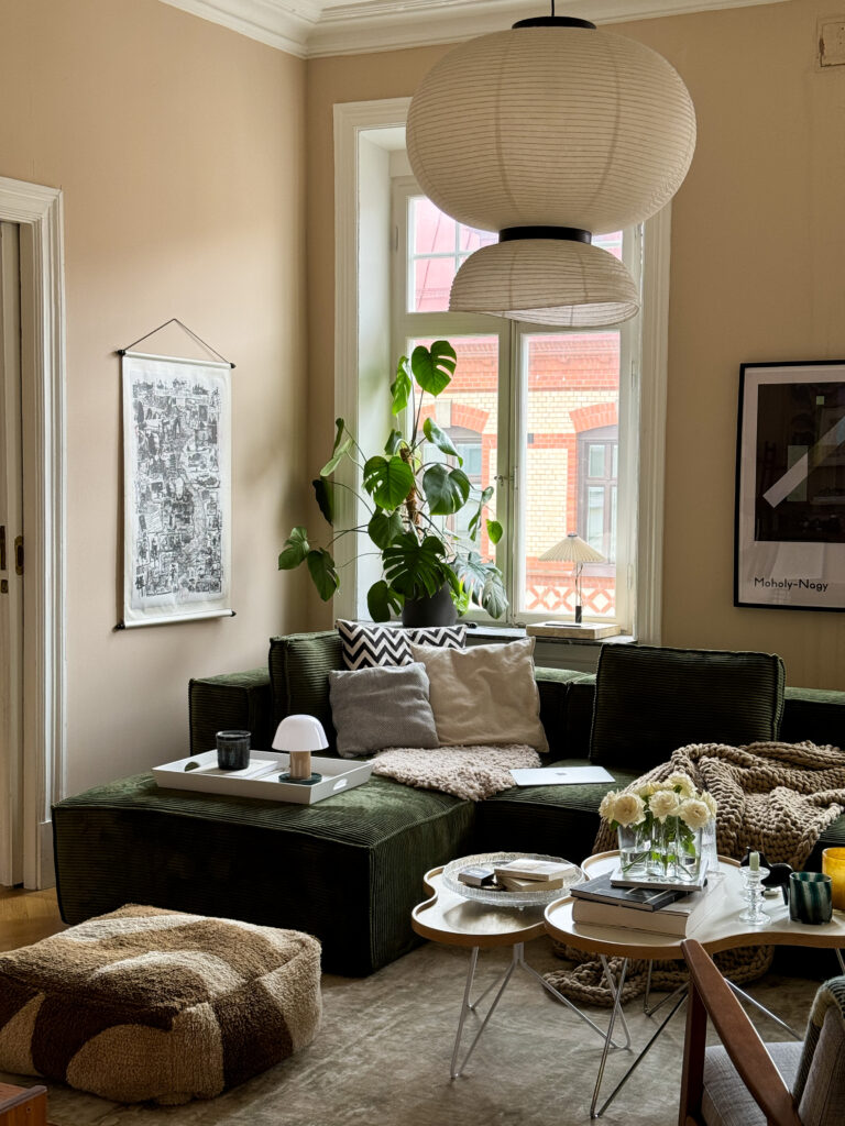 Green big manchester sofa in a scandinavian home with beige walls and a big rice lamp