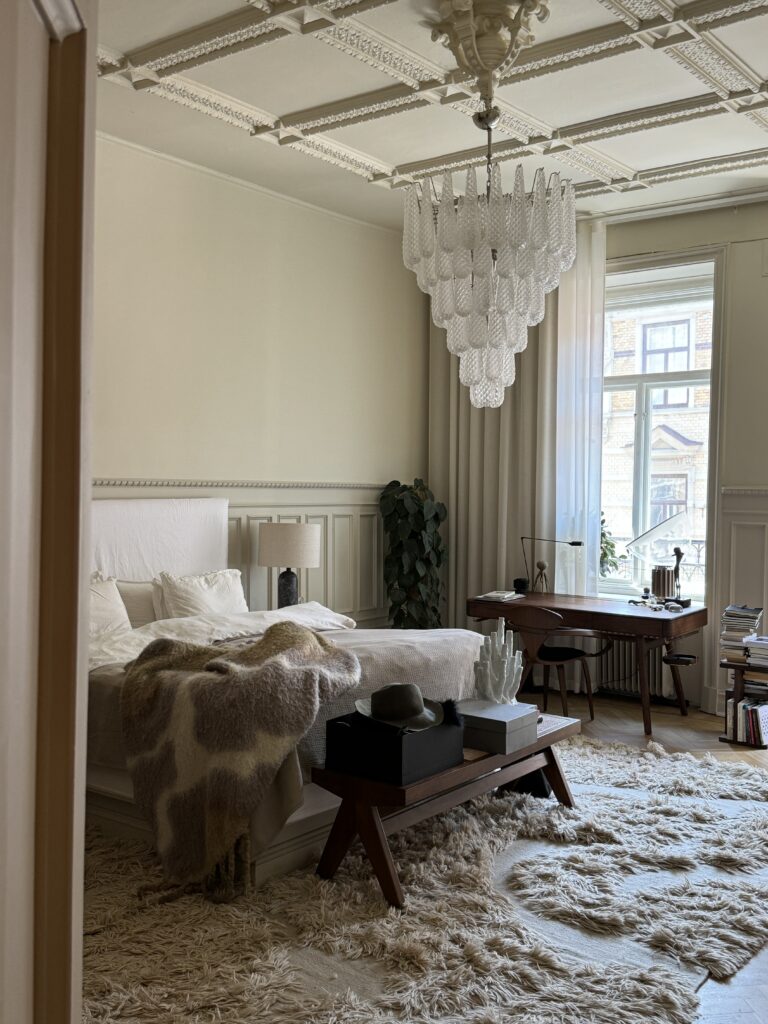 Elegant and luxurious bedroom with turn of the century details like a high ceiling anda big murano chandelier.