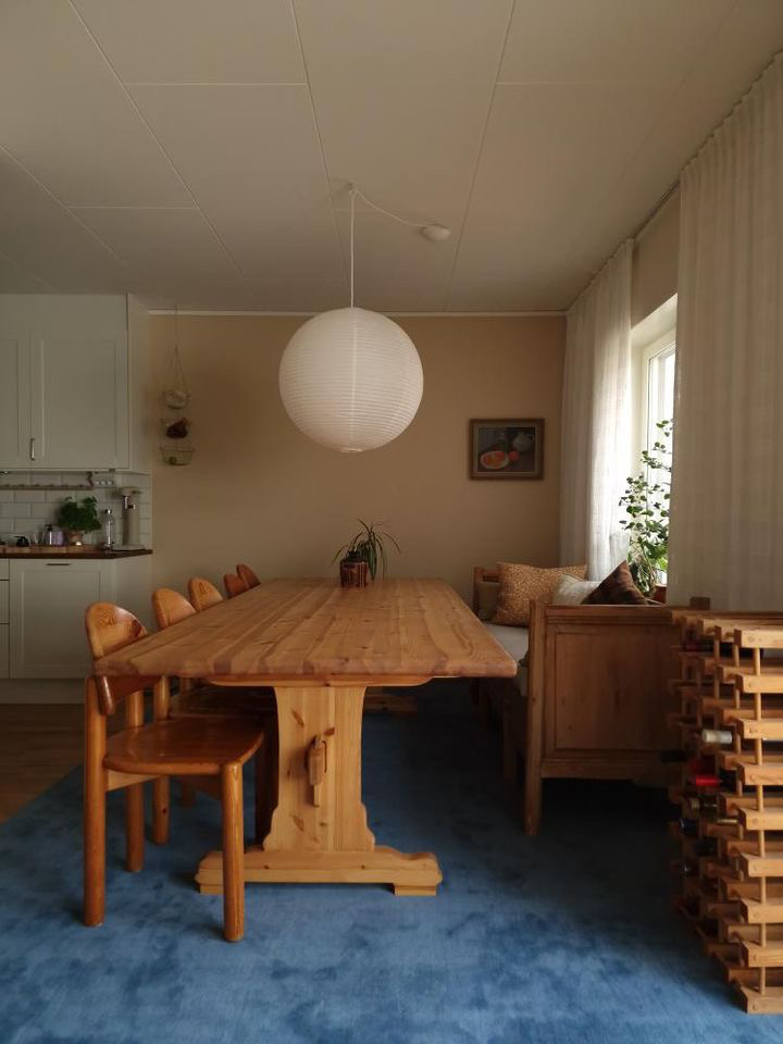 Kitchen sofa in natural wood in Scandinavian warm home with blue rug and beige warm walls.