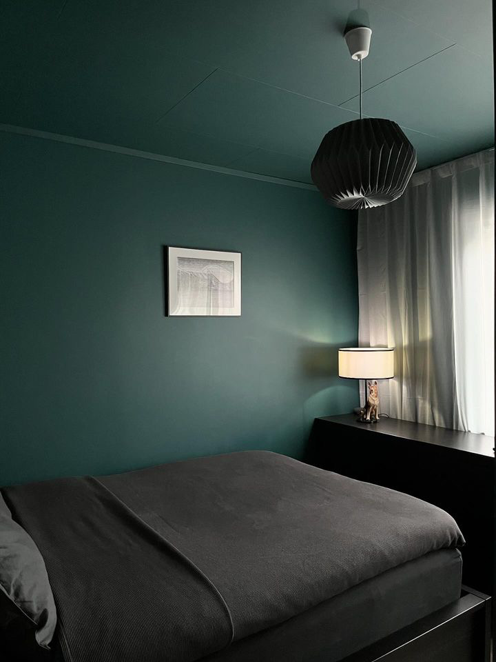 Bedroom painted in the same dark teal color on the walls and ceiling for a cozier feeling.