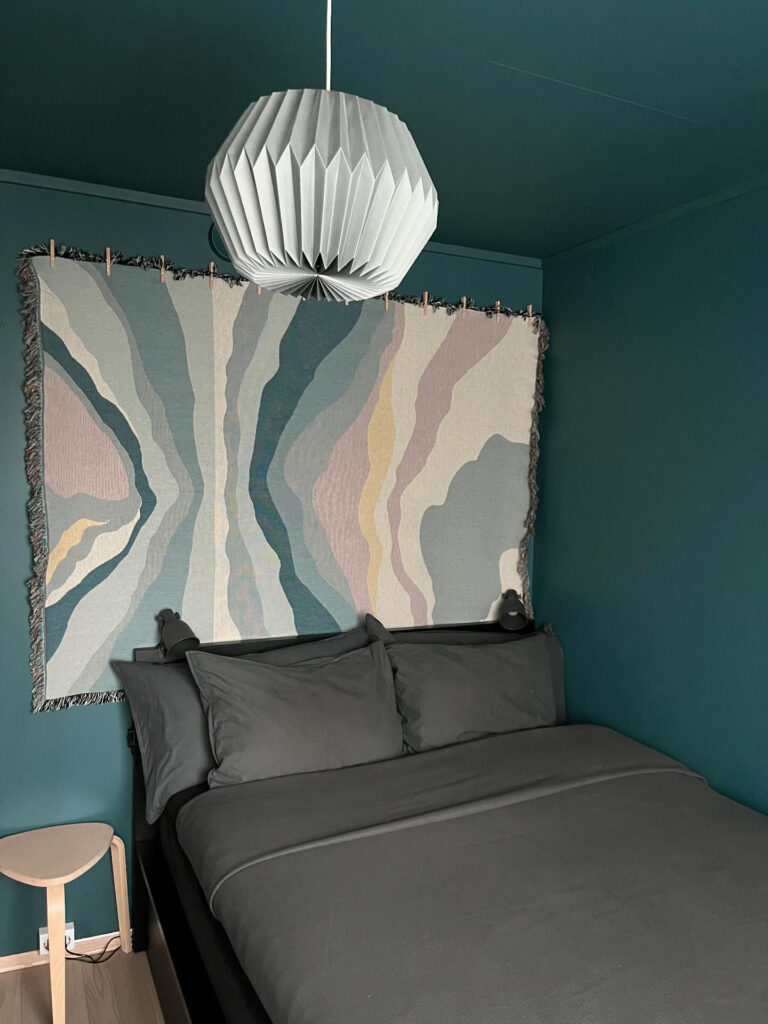 Color drenched bedroom in a dark teal color that makes the room feel cozy.